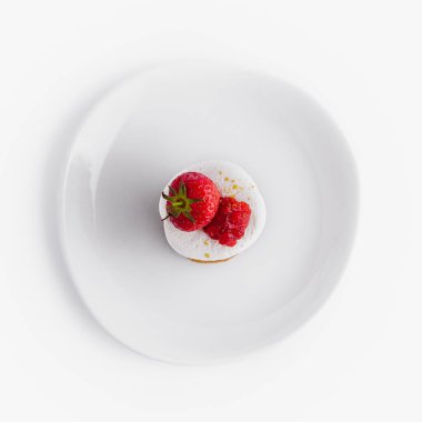 Tek olgun çilek, beyaz tabakta tozlanmış tatlı, üst manzara.