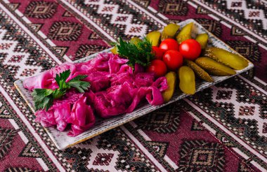 Etnik desenli kumaşa yerleştirilmiş renkli lahana, salatalık ve domates turşusu.