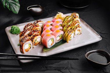 Yemek çubukları ve soya sosuyla servis edilen çeşitli soslu suşi dürümleri.