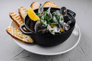 Bir kase haşlanmış midye otlarla süslenmiş ızgara ekmek ve limonla servis edilmiş.