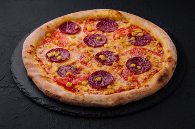 Lezzetli taze pişmiş pepperonili pizza. Koyu bir levhada altın peynirli.