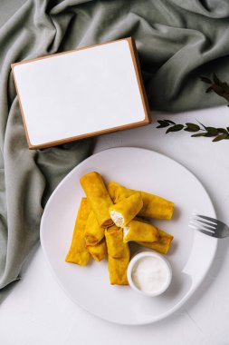 Beyaz masa örtüsü üzerine sos serpiştirilmiş ev yapımı böreklerin mükemmel sunumu.