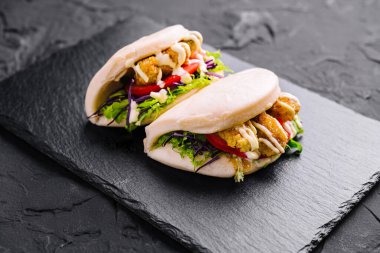 Tavukla dolu tuzlu bao çörekleri ve siyah bir arka planda taze salatalar.