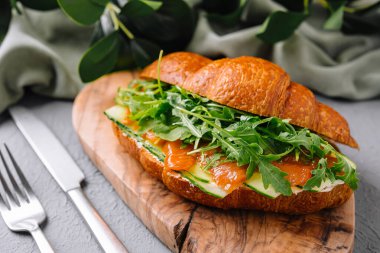 Taze kruvasan, füme somon ve roka. Köy tahtasında servis ediliyor.