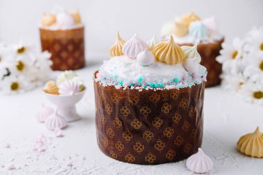 Zarif paskalya pastası krema, krema ve pastel şekerlerle süslenmiş, narin çiçeklerle çevrili.