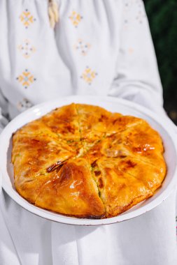 Geleneksel kıyafetle yapılan ev yapımı lezzetli bir turtanın yakın çekimi.