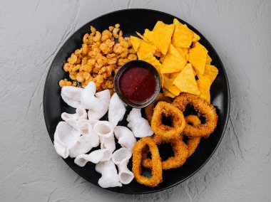 Cips, soğan halkaları ve siyah tabağa batırılmış çerez seçiminin üst görüntüsü