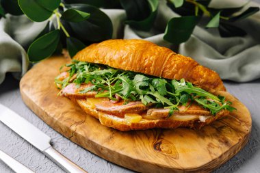 Tahtada pastırma, roka ve peynirle dolu lezzetli kruvasan sandviçi.