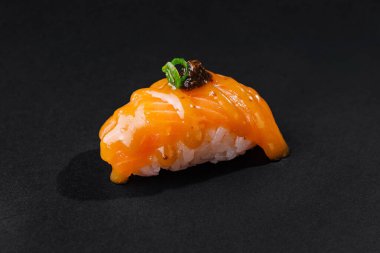 Yeşil soğan ve trüf mantarıyla süslenmiş güzel hazırlanmış somon nigiri suşisi.