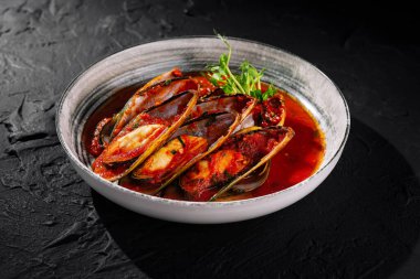 Baharatlı domates soslu ve taze otlarla süslenmiş lezzetli midyeler.