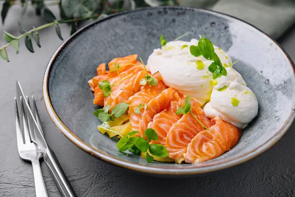 Dish of smoked salmon and poached eggs garnished with fresh herbs on a stylish plate