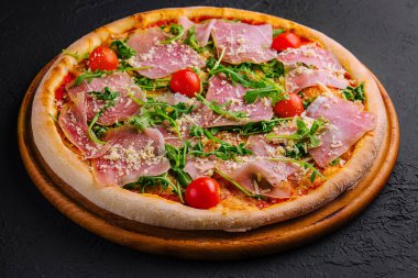 Prosciutto, vişneli domates, roka ve parmesanlı taze pişmiş pizza.