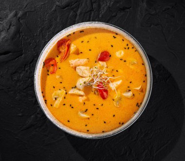 Zengin ve kremalı Tayland usulü, garnitürlü tavuk körisi, koyu bir levha yüzeyinde servis edilir.