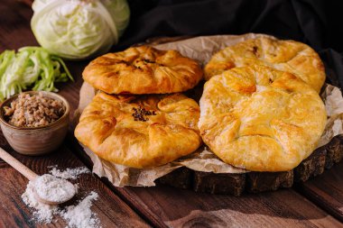 Kırsal ahşap arka planda otlar ve lahanalarla süslenmiş altın Gürcü khachapuri ekmeği.