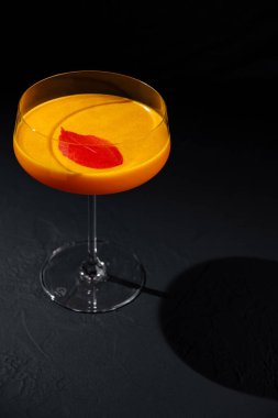 Zarif koyu bir yüzeyde sunulan narenciye kıvrımlı, sofistike turuncu kokteyl.