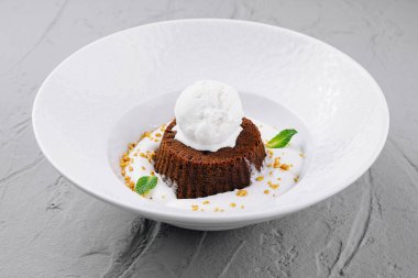 Vanilyalı dondurmayla kaplanmış, nane yapraklarıyla süslenmiş gurme çikolatalı lav keki.