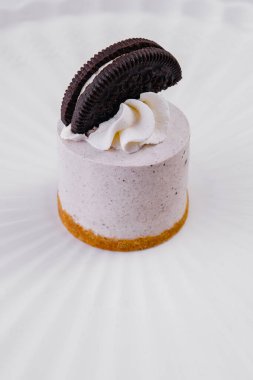 Krem şantili mini cheesecake tatlısı ve beyaz arka planda çikolatalı kurabiye.