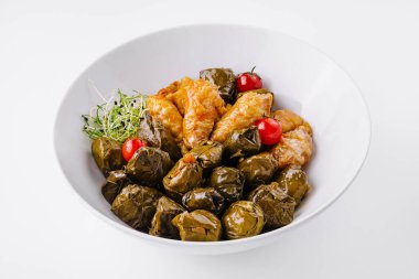 Delicious dolmas, rice-stuffed grape leaves, garnished with cherry tomatoes and herbs clipart
