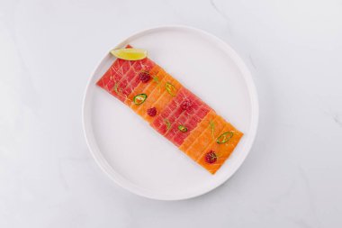 Limon ve jalapeo dilimleriyle süslenmiş bir tabak somon carpaccio.