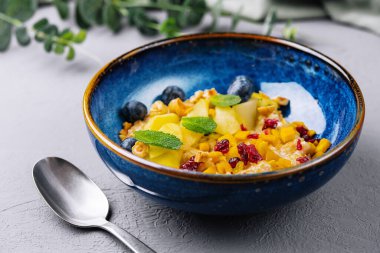 Zarif bir mavi kasede servis edilen naneli süslemeli renkli meyve salatası.