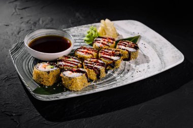 Susam tohumlarıyla kaplı nefis suşi seçimi. Soya sosu, wasabi ve zencefil ile servis ediliyor.