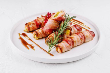 Peynirle dolu domuz pastırmasına sarılmış biberiye ile süslenmiş biberiye.