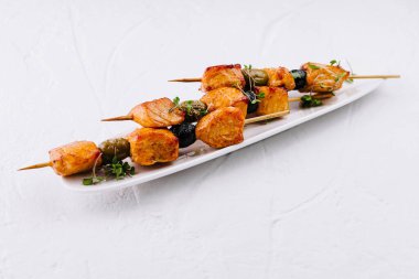 Zarif bir tabakta otlarla süslenmiş tavuk şişleri sunumu.