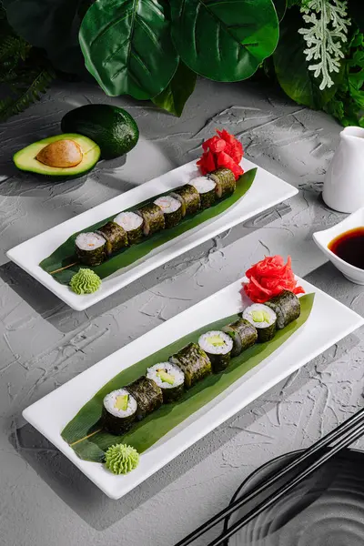 用芥末和生姜装饰在现代盘子上的鳄梨寿司卷 可随时上桌 — 图库照片