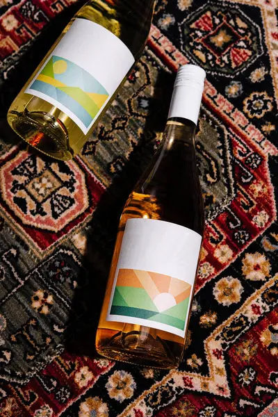 stock image Two bottles of wine with modern labels resting on a richly patterned persian rug