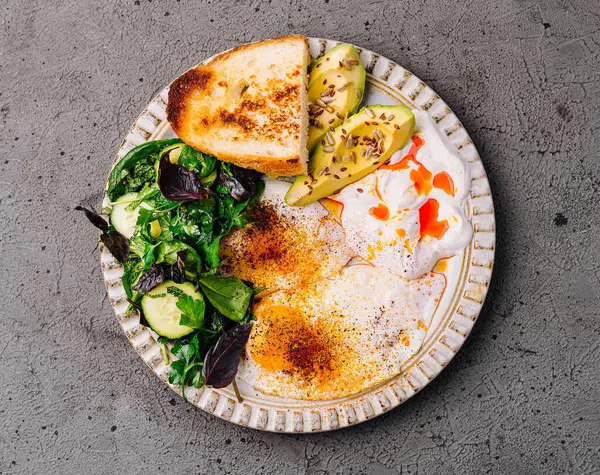 Haşlanmış yumurta, avokado dilimleri ve acı sosla ıslatılmış yeşillikler.