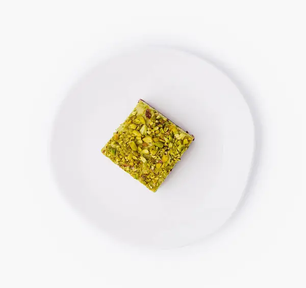 Beyaz arka planda izole edilmiş temiz beyaz bir tabakta fıstık aromalı lezzetli bir hamur işi.