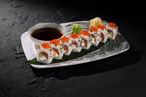 Exquisite sushi rolls topped with caviar, served with soy sauce, wasabi, and ginger on a sleek plate