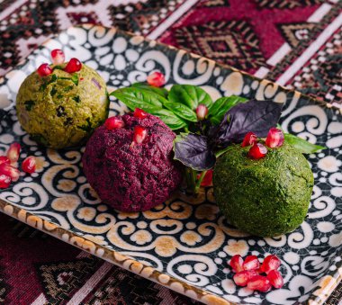 Nar tohumları ve taze fesleğenle süslenmiş, desenli bir tabakta servis edilen nefis vejetaryen aperatifi.