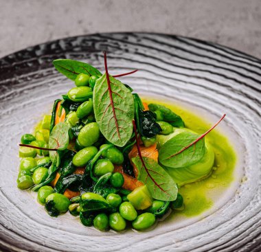 Canlı yeşilliklerle dokulu bir tabakta sunulmuş gurme edamame fasulye salatası