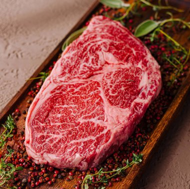 Çiğ, mermer pirzola biftek otlar ve baharatlarla süslenmiş, pişirilmeye hazır.