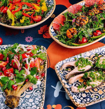 Akdeniz yemeklerini taze sebzeler ve dekorla desenli bir masa örtüsüne serdim.