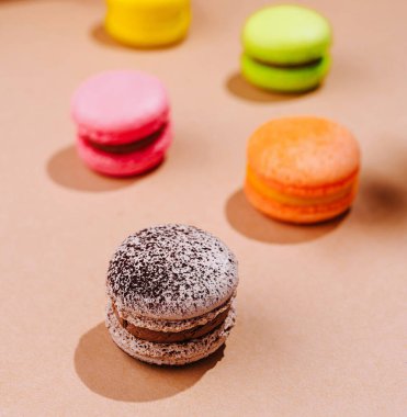 Canlı Fransız badem kurabiyeleri bej bir yüzeye ustalıkla dizilmiş.