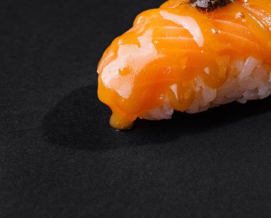 Lezzetli bir somon nigiri sushi 'nin yakın plan resmi. Arkaplanda biraz wasabi süslemesi var.