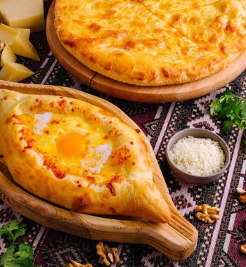 Taze malzemelerle çevrili yumurta ve peynirli pizzayla muhteşem bir Adjarian Khachapuri ziyafeti.
