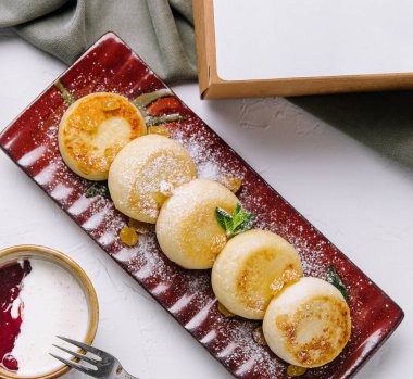 Pudra şekerli gurme kreplerin üst görüntüsü, daldırma sosu ve yeşil dekorla birlikte.