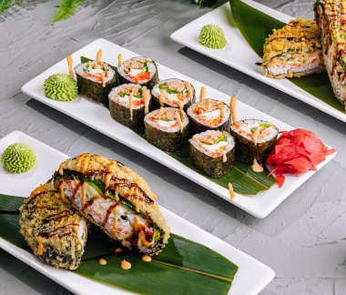 Bambu yaprakları, soya sosu ve wasabi ile servis edilen suşi rulolarının zarif sunumu.