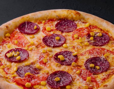 Lezzetli taze pişmiş pepperonili pizza. Koyu bir levhada altın peynirli.