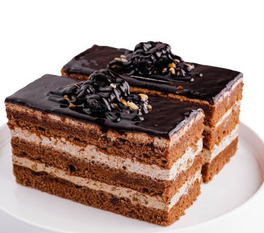 Işıltılı krema ve talaşla kaplı iki dilim zengin katmanlı çikolatalı pasta.