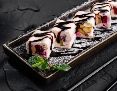 Tabakta çikolata soslu sanatsal meyve suşisi.