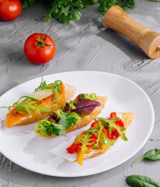 Üç renkli bruschetta aperatifi. Taze yeşillik ve fındıkla süslenmiş.