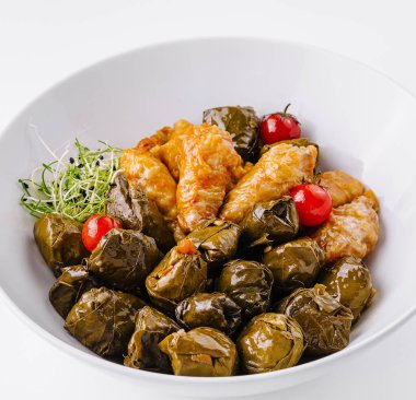 Lezzetli dolmas, pirinç doldurulmuş üzüm yaprakları, kiraz domatesleri ve otlarla süslenmiş.