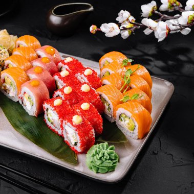 Suşi çeşitleri, siyah arka planda süslerle sanatsal olarak kaplanmış.