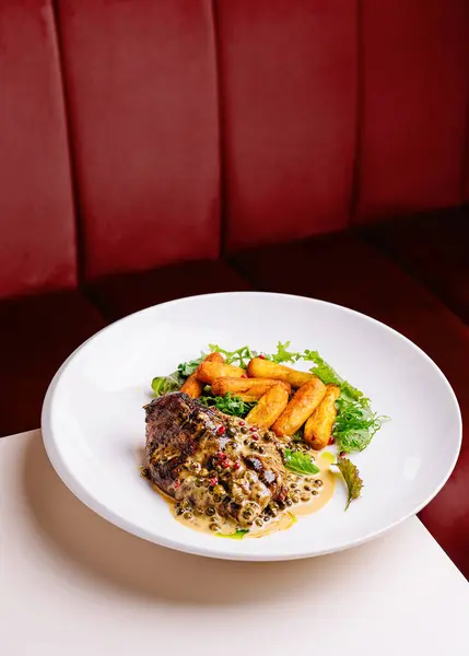 Delicious plate of seared steak, creamy peppercorn sauce, and golden fries, ready to be enjoyed