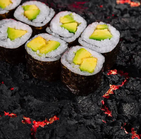 stock image Exquisite avocado sushi rolls artfully presented on a vibrant lava-like textured background