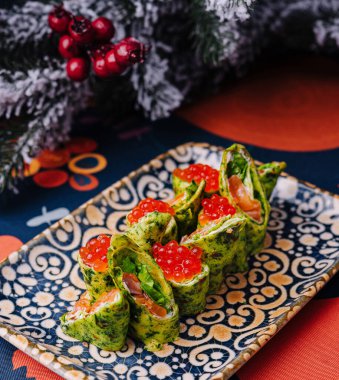 Şatafatlı bir arka planda, dekoratif bir tabakta sunulan, üzerinde lüks somon yumurtası bulunan canlı ıspanaklı krepler.